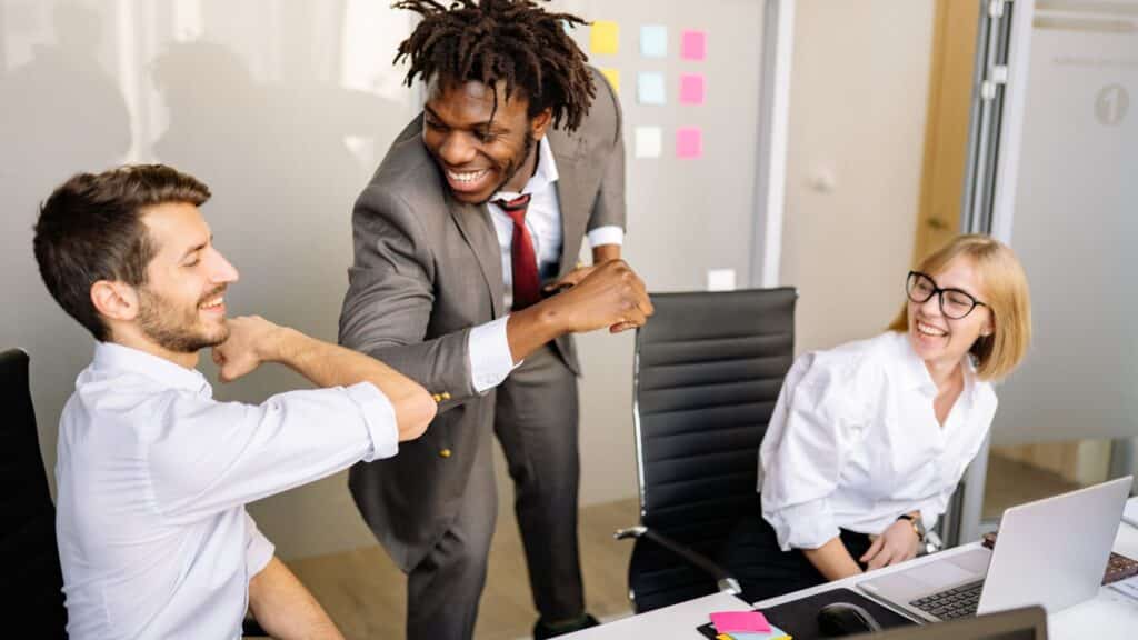 Business professionals celebrating successful stress-free commercial moving process in Denver office with colorful sticky notes on whiteboard in background.