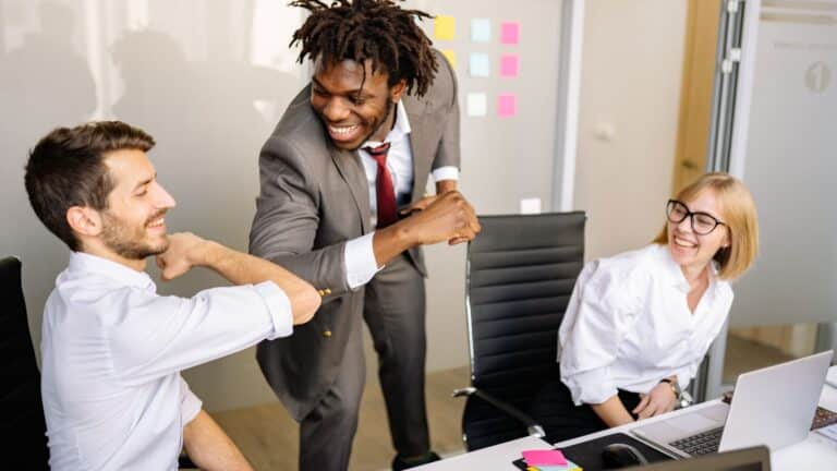 Business professionals celebrating successful stress-free commercial moving process in Denver office with colorful sticky notes on whiteboard in background.