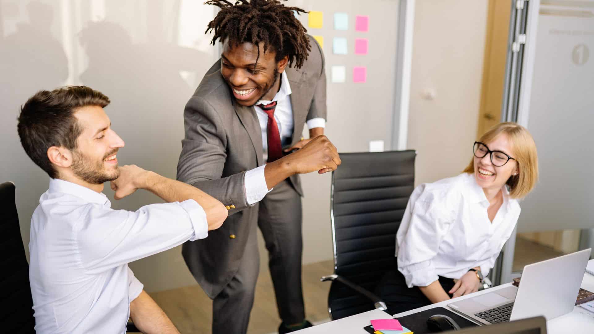 Business professionals celebrating successful stress-free commercial moving process in Denver office with colorful sticky notes on whiteboard in background.