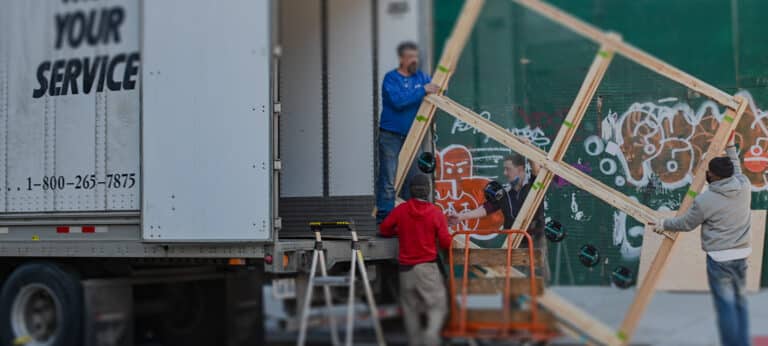 Four men loading a big piece of furniture into a moving van