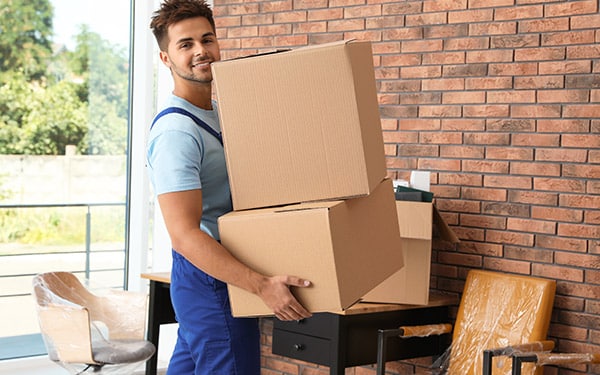 Professional mover carrying a large cardboard box.