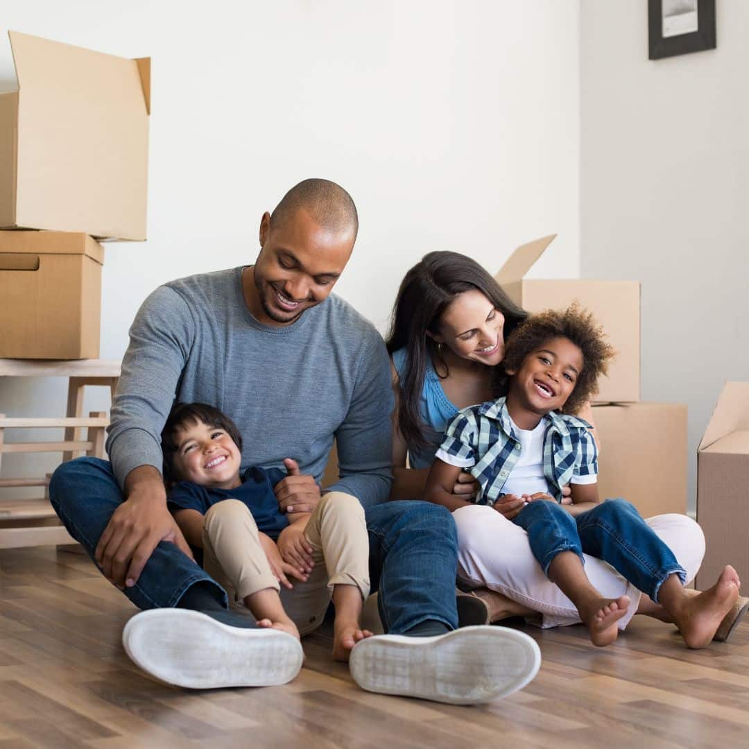 Family of four sitting near moving boxes