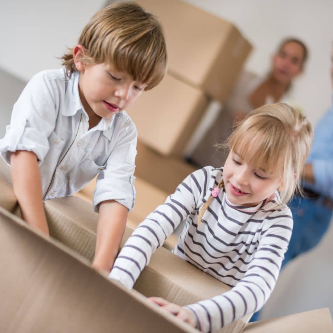Two young kids packing a moving box