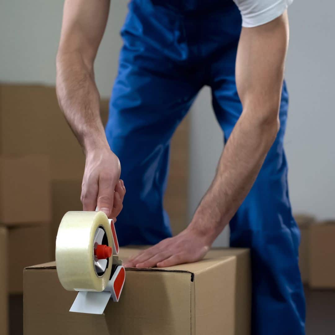 A mover taping a moving box closed.