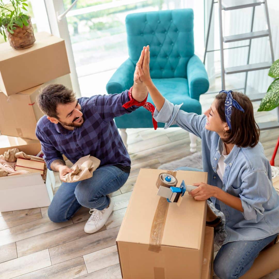 couple high-fiving each other while packing moving boxes