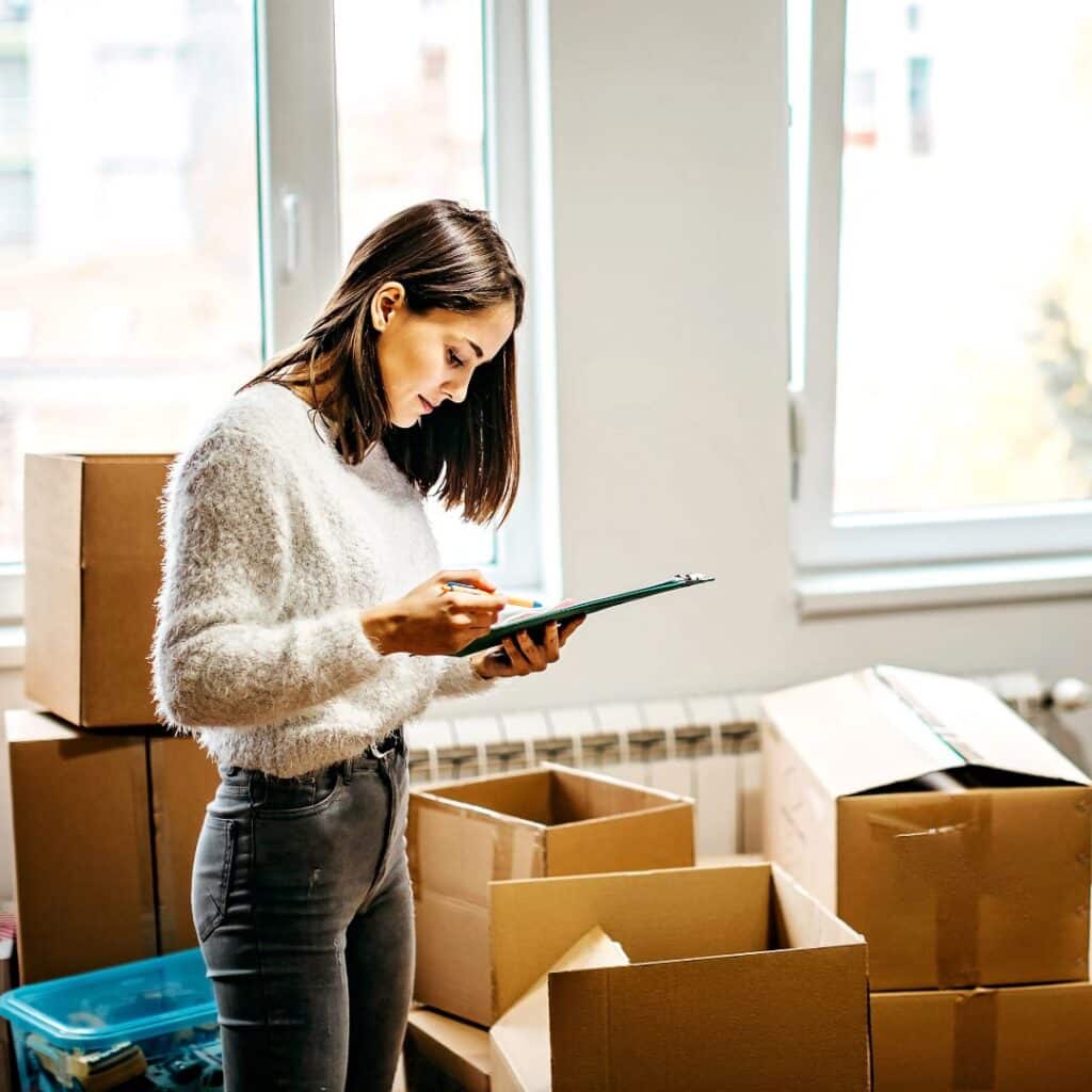 A young woman with a checklist preparing boxes to move