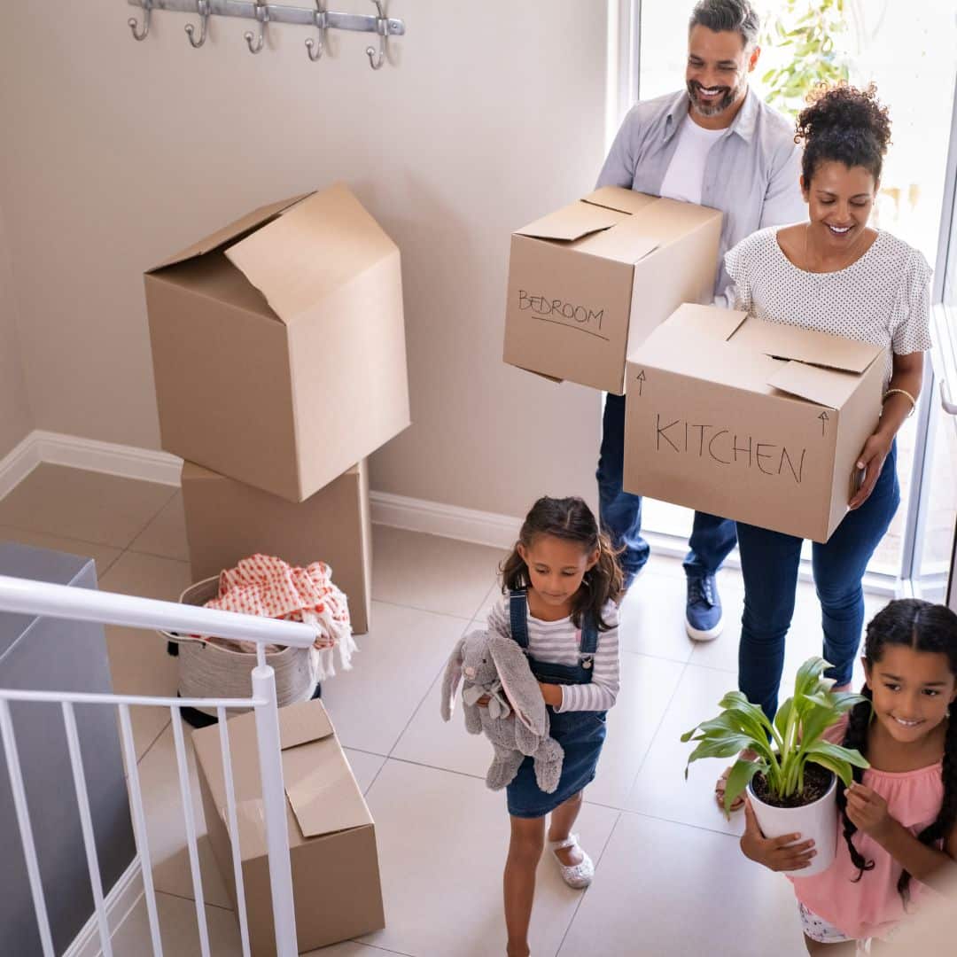 family carrying boxes into new home