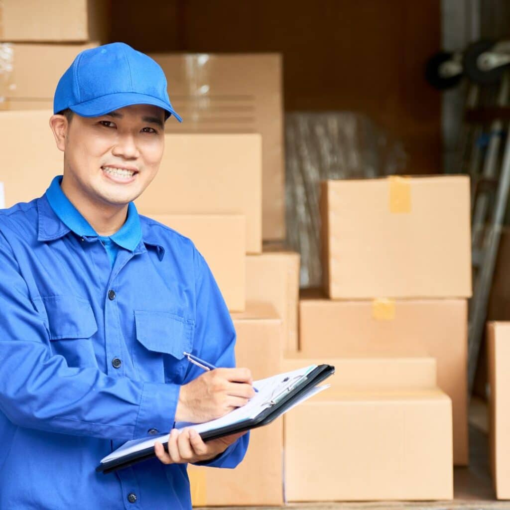 A professional mover from Abe Lincoln Movers holding a clipboard, standing in front of packed boxes ready for transport.