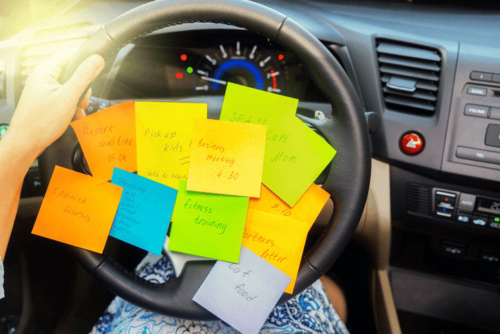 A person driving with several post-it notes on their steering wheel