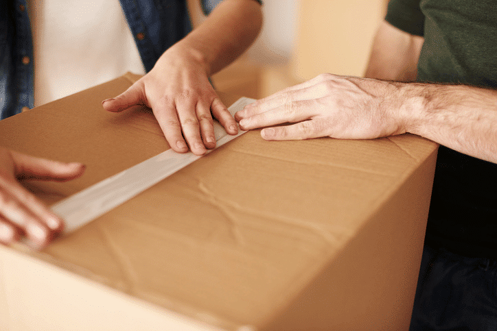 Two people taping up a moving box