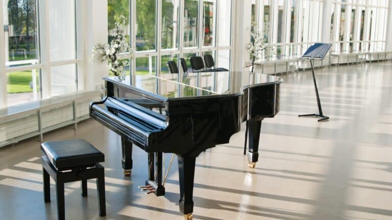 Black grand piano in a bright, modern event space, highlighting the expertise and care required from specialty professional piano movers to safely transport such valuable and delicate instruments.