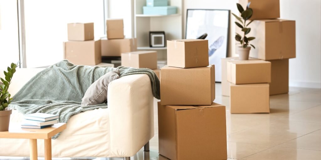Packed moving boxes and furniture in a living room during the process of moving out of a rental in Denver.