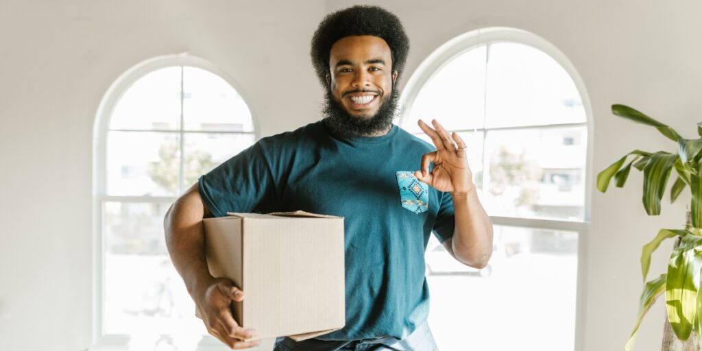 Professional mover smiling while holding a box, ready to share apartment moving tips for renters in Denver.
