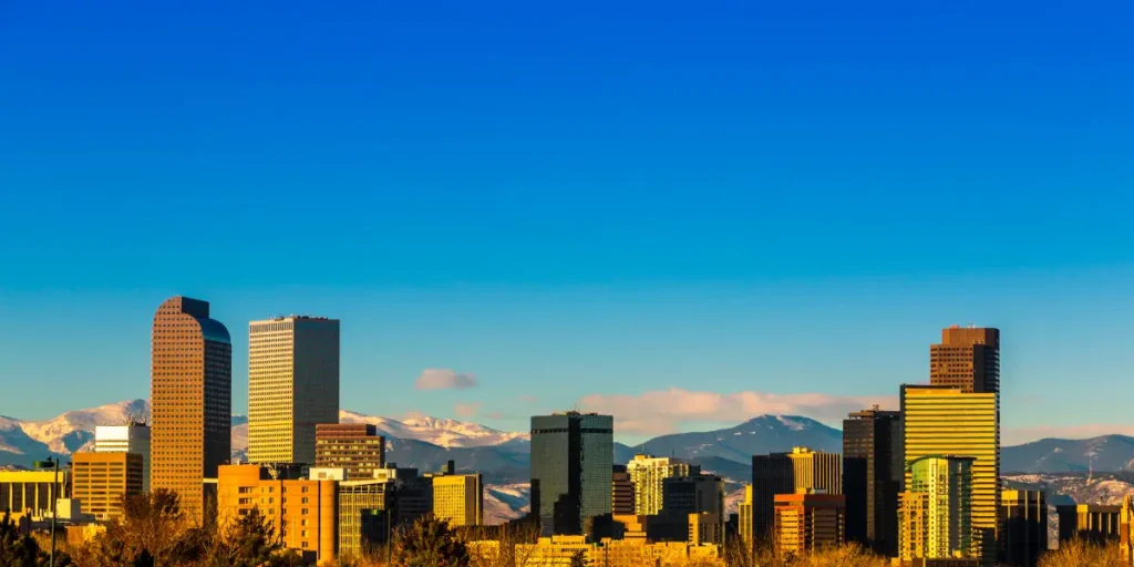 Denver Colorado skyline with downtown skyscrapers and Rocky Mountains in background during golden hour