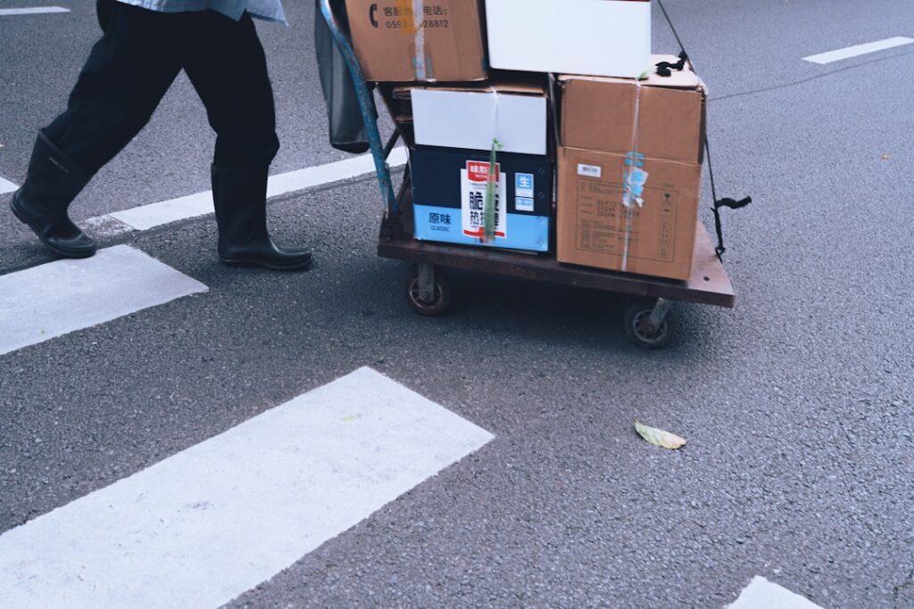 A large moving truck parked outside a house with moving boxes stacked nearby, symbolizing relocation services.
