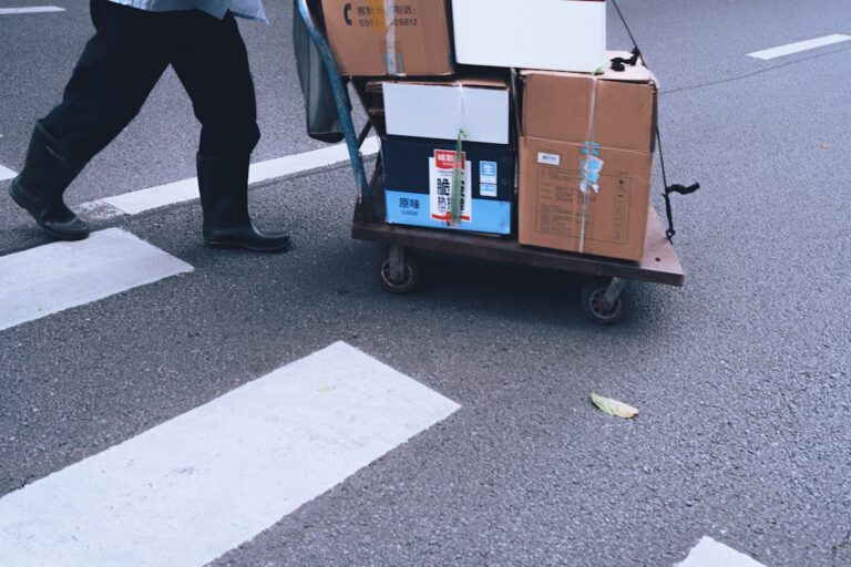 A large moving truck parked outside a house with moving boxes stacked nearby, symbolizing relocation services.