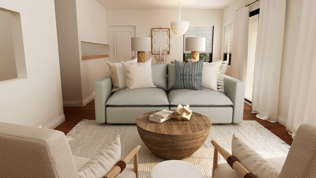 A brightly lit but disorganized living room with stacks of cardboard boxes, packing tape, and furniture covered in sheets, depicting the chaos of moving.