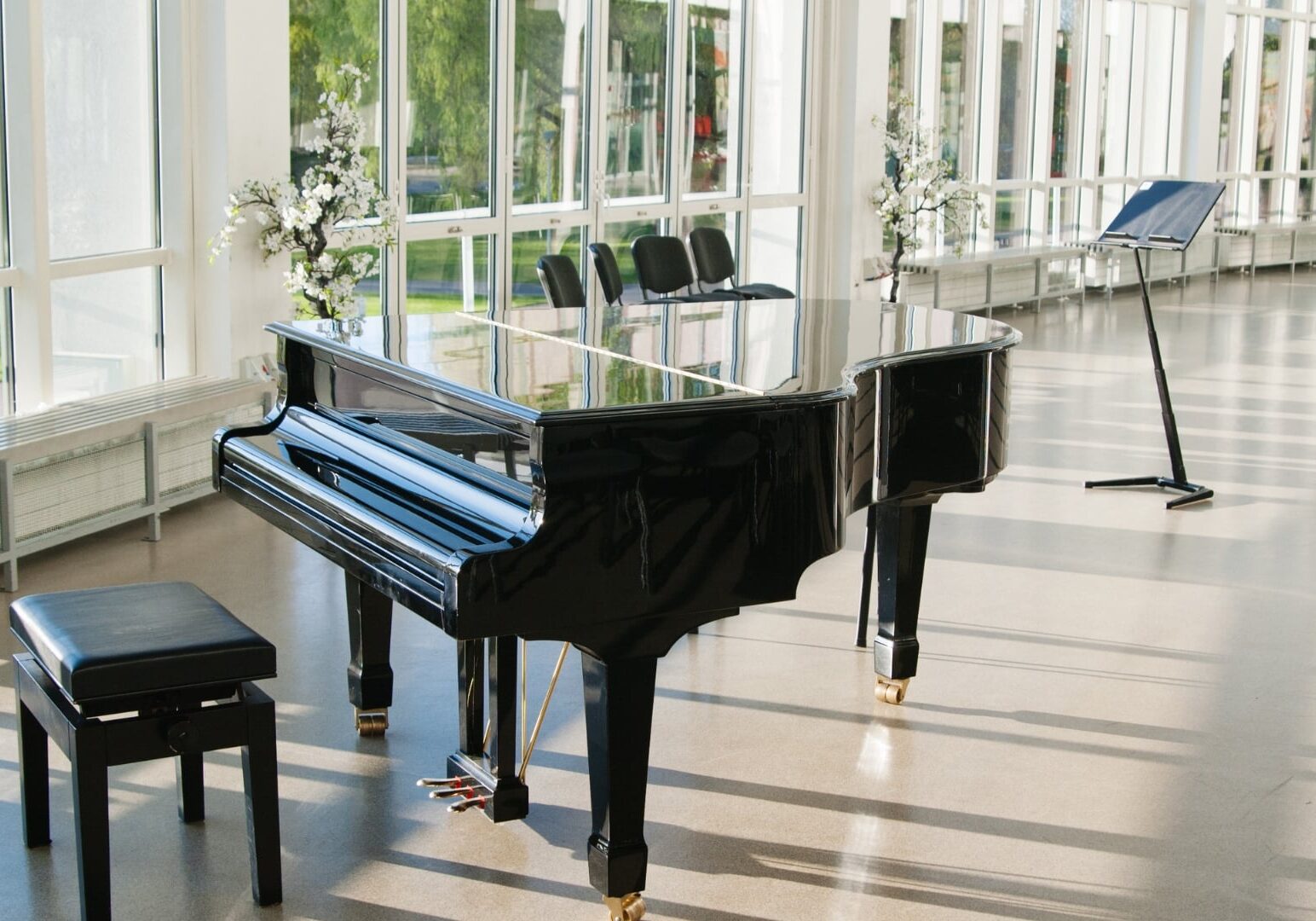 Black grand piano in a bright, modern event space, highlighting the expertise and care required from specialty professional piano movers to safely transport such valuable and delicate instruments.