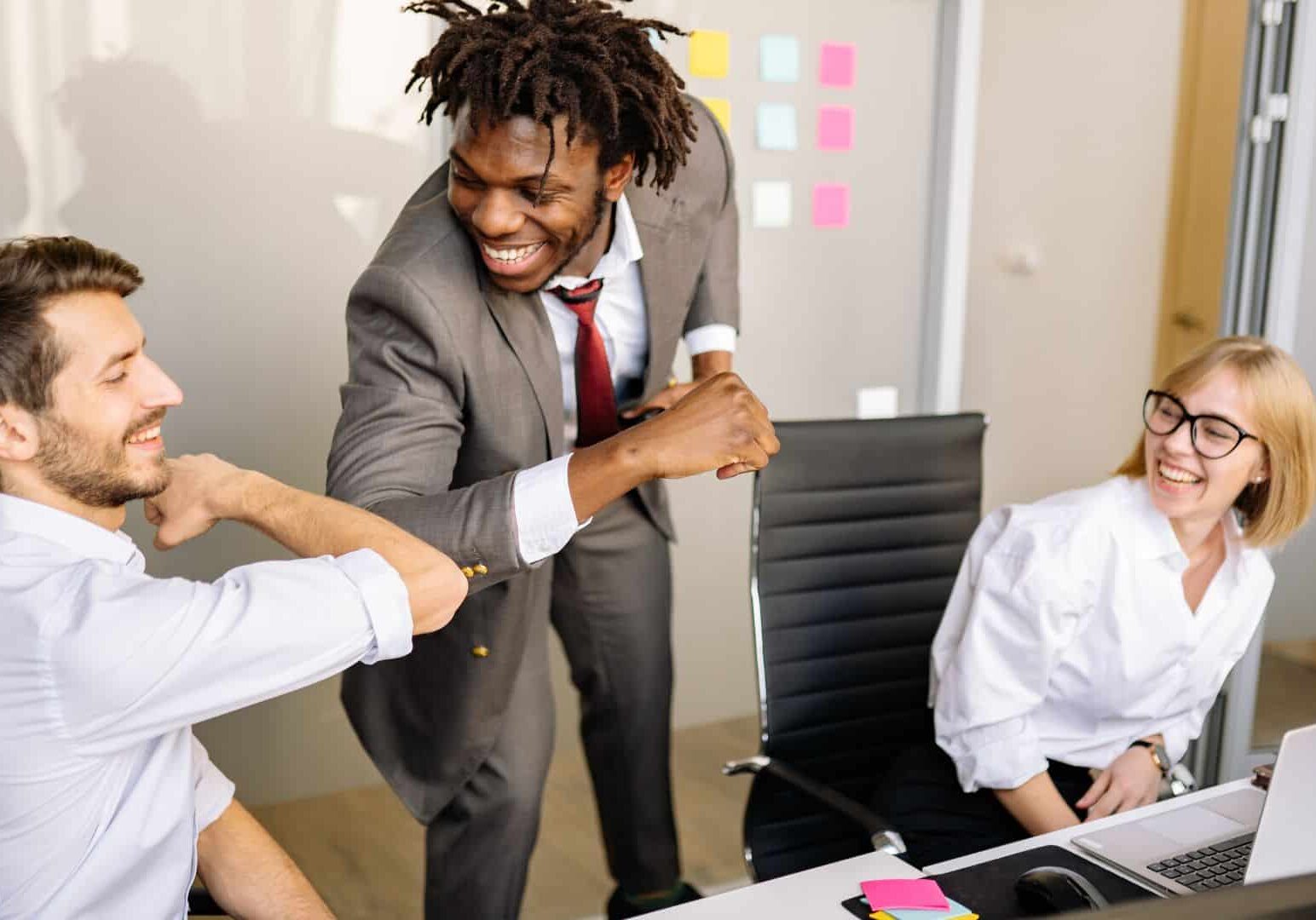 Business professionals celebrating successful stress-free commercial moving process in Denver office with colorful sticky notes on whiteboard in background.
